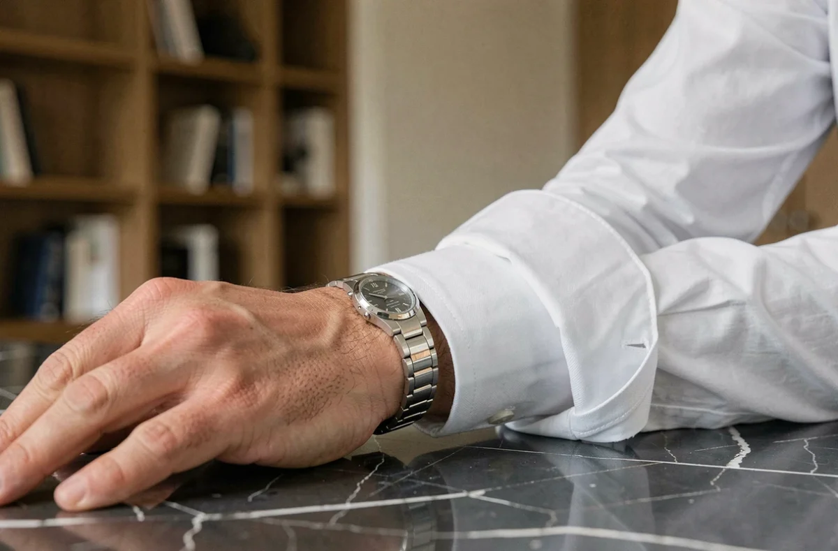 Homme élégant portant un bracelet en or blanc sur une surface en marbre noir dans un bureau minimaliste moderne